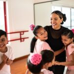 Dance teacher gives her smiling students a hug