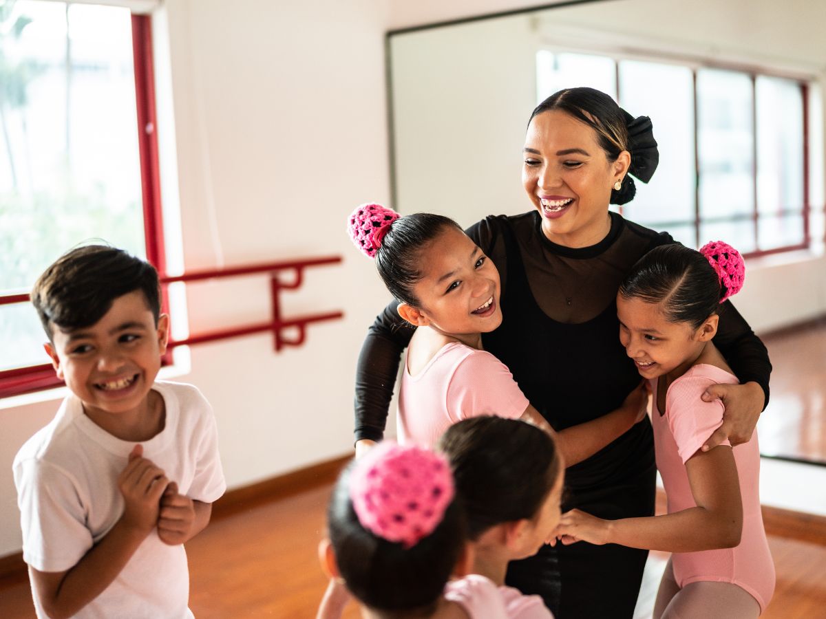 Dance teacher gives her smiling students a hug